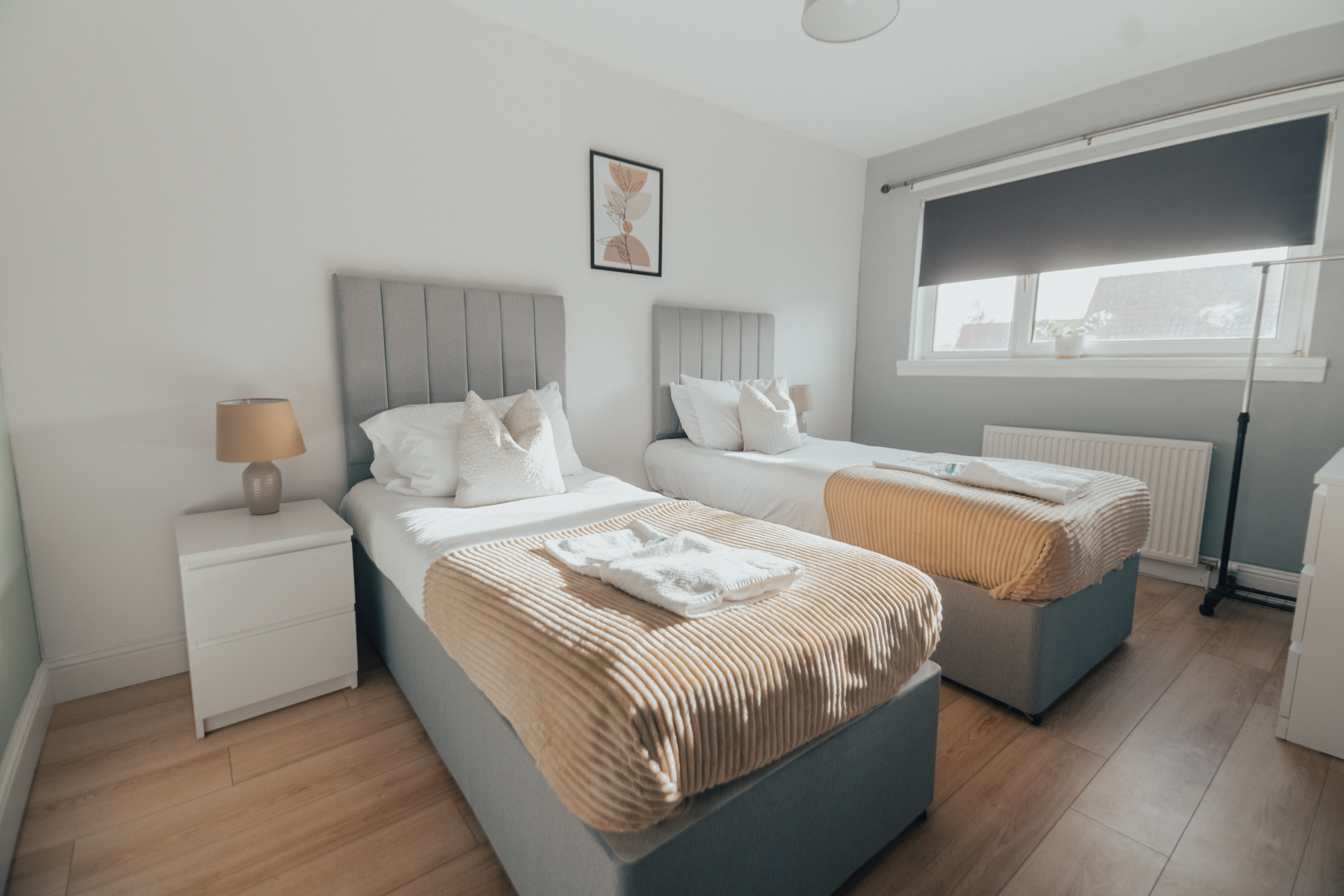 Twin bedroom prepared for guests, with fresh white linen and towels folded on both beds