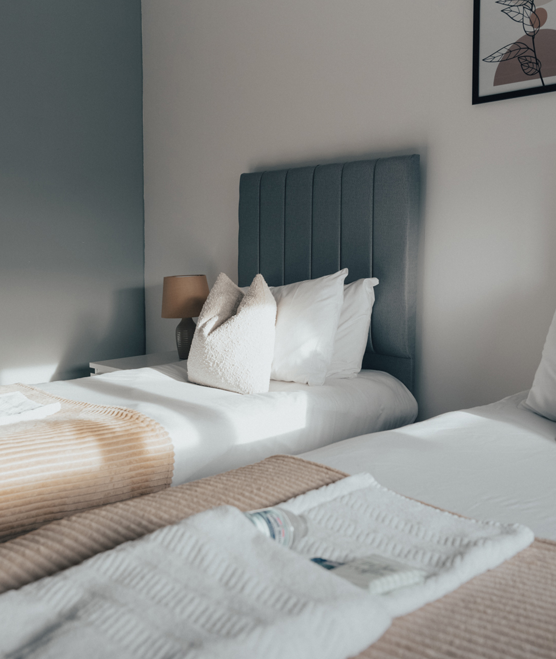 Two single beds made up with fresh linen, folded towels and guest toiletries
